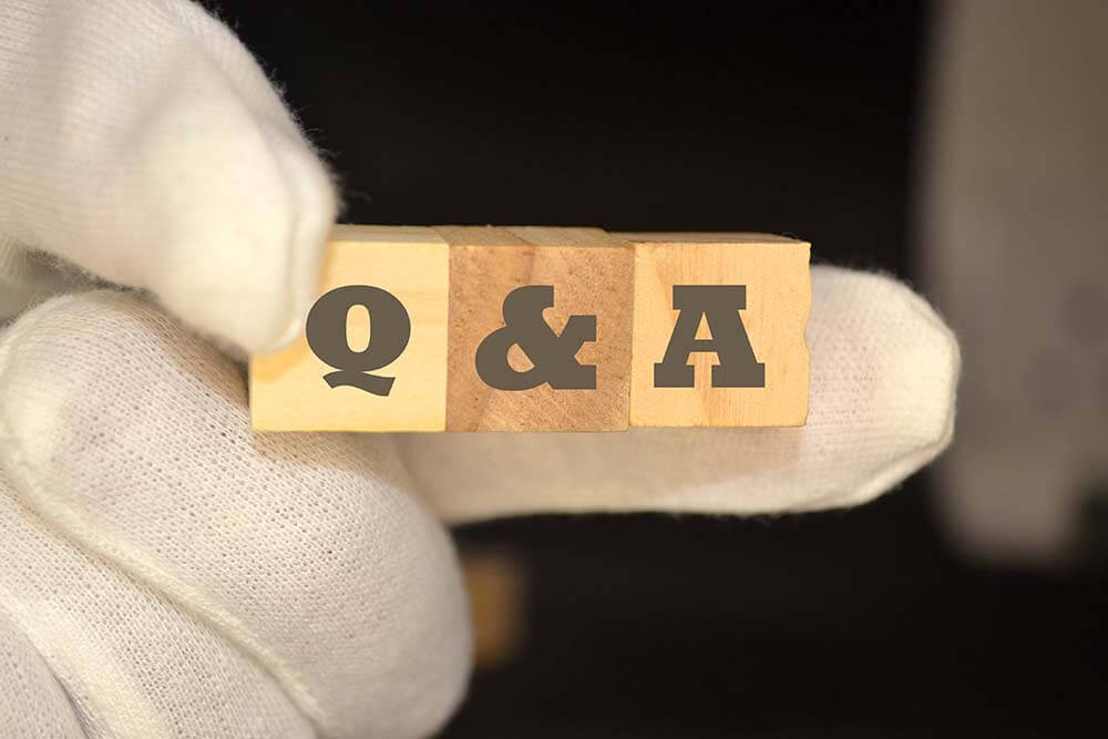 Рука тримає дерев'яні блоки Q&A представляючи вичерпні питання покупців нерухомості та експертні