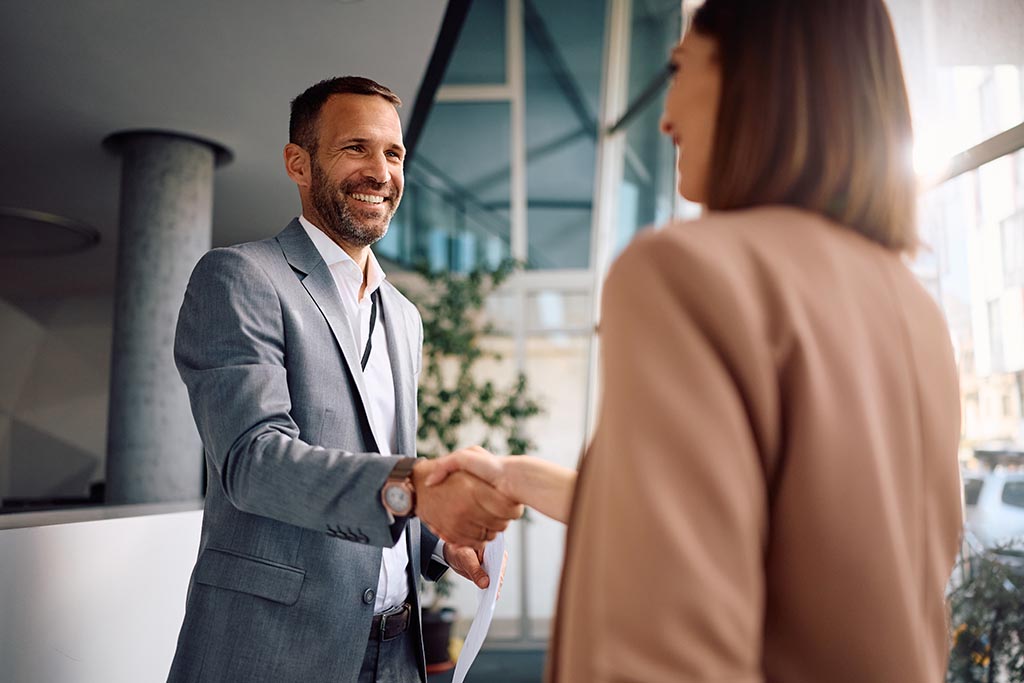 Чоловік і жінка тиснуть руки, фіксуючи офіційну угоду про купівлю нерухомості в Болгарії